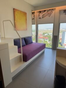 King Deluxe room at Wink Hai Phong with a couch, a twin bed in a nook and floor-to-ceiling windows