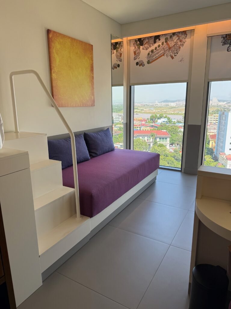 King Deluxe room at Wink Hai Phong with a couch, a twin bed in a nook and floor-to-ceiling windows