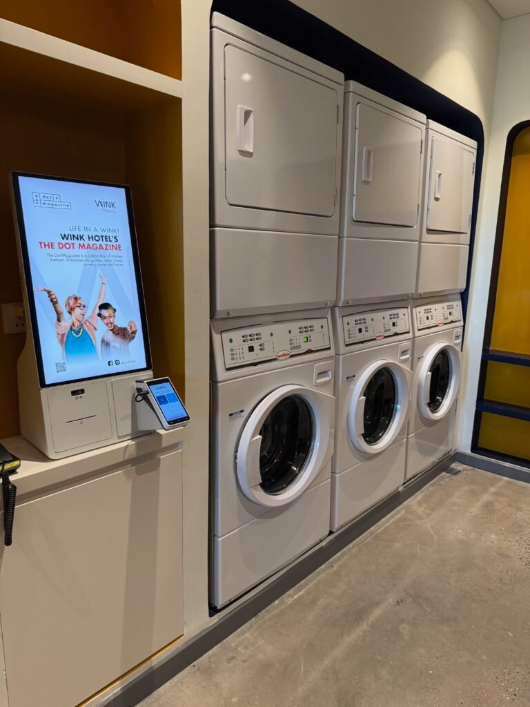 24-hour self-service laundromat with washers, dryers and a payment kiosk